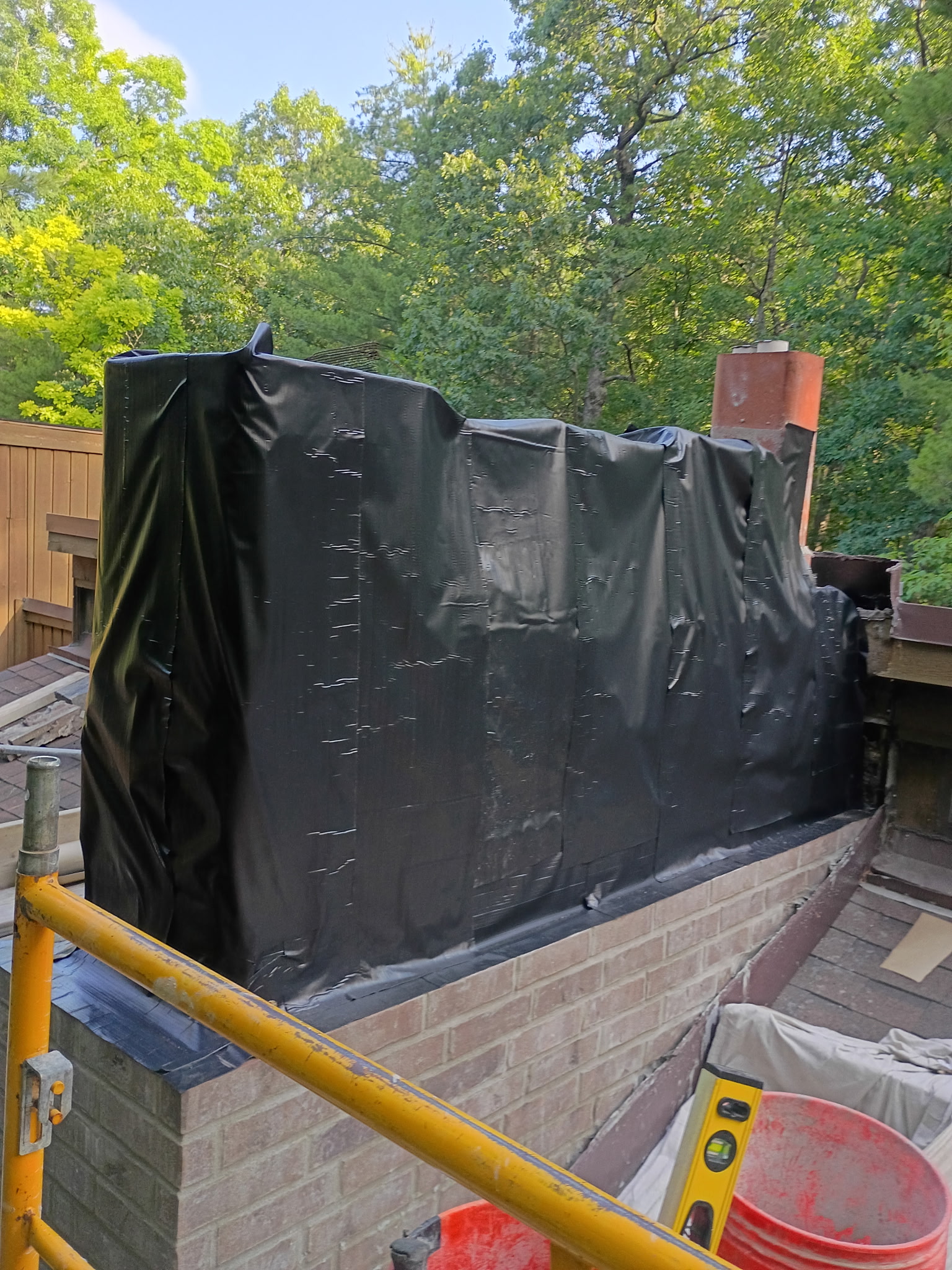Large chimney mid-rebuild wrapped in weatherproof sheeting on scaffolding